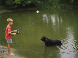 Boy Fishing in a Pond with a Black Labrador Retriever Standing in the Water Photographic Print by Brian Gordon Green