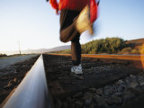 An Athlete Runs on Railroad Tracks Toward the Mountains Photographic Print by Joy Tessman
