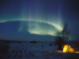 The Northern Lights Shine over a Campsite Photographie par Paul Nicklen