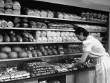 Good of Worker in Bakery Standing in Front of Shelves of Various Kinds of Breads and Rolls Premium Photographic Print by Alfred Eisenstaedt