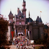 Crowds Walking Through Gate of Sleeping Beauty's Castle at Walt Disney's Theme Park, Disneyland Photographic Print by Allan Grant