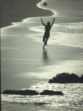 Young Woman in Silhouette Running Along Beach at Twilight Throwing Beach Ball Up in the Air Premium Photographic Print by Co Rentmeester