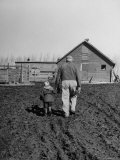 Grandpa and 4 Year Old Granddaughter, on Morning Chores, to Feed Pigs on Nearby Lot Photographie par Gordon Parks