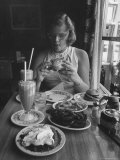 Teenaged Girl Sitting in Drugstore Eating a Hamburger Reproduction photographique sur papier de qualité par Hank Walker