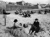 Wrapping Up Against the Cold on Blackpool Beach Reproduction photographique sur papier de qualité par Ian Smith