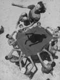 Teenaged Boys Using Blanket to Toss Their Friend, Norma Baker, Into the Air on the Beach Premium Photographic Print by John Florea