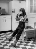 Young Girl Wearing Cowgirl Outfit Drinking Milk and Eating Sandwich in Kitchen Photographic Print by Nina Leen