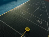 Setting up for a Shot on a Shuffleboard Game on a Cruise Ship Lámina fotográfica por Todd Gipstein