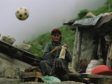 A Soccer Ball Flies over the Head of Woman Who is Knitting Outdoors Photographic Print by Randy Olson