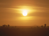 The Setting Sun Casts a Hazy Orange Glow over the Sahara Desert Photographic Print by Peter Carsten