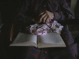 An Old Womans Hands Lie on a Book That She is Reading Photographic Print by Roy Gumpel