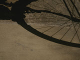A Bicycle Wheel Casts a Shadow on a Wall and Sidewalk in Siena Photographic Print by Raul Touzon