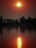 A Fiery Sun Rises Above the Tree-Lined Shore of the Wye River Photographie par Stephen St. John