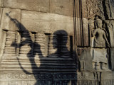 The Silhouetted Shadow of a Man Holding an Automatic Rifle is Cast against a Cambodian Temple Wall Photographic Print by Paul Chesley