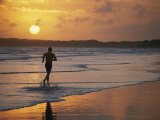 A Man Runs Through the Surf on Shella Beach at Sunset Photographie par Bobby Model