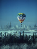 Hot Air Balloon Hovers Over a Snowy Landscape Lámina fotográfica
