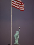 A Rear View of the Statue of Liberty and a Fluttering American Flag Photographic Print