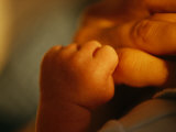 Close View of the Hands of an Infant and Parent Photographic Print by Raul Touzon