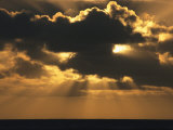 Rays of Sunlight Beam from Behind a Dark Cloud over Water at Twilight Photographic Print by Tim Laman