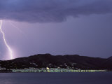 A Lightning Bolt Strikes the Mountains Behind a Town of Costa Brava Photographic Print by Pablo Corral Vega