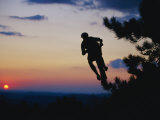 Silhouette of Mountain Biker in the Air against Sunset Sky Photographic Print by Skip Brown