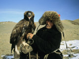 Un chasseur à l'aigle Kazakh pose avec son aigle dans une plaine du Kazakhstan Photographie par Ed George