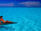 Woman Basking in the Sun on an Outrigger Boat in an Island Lagoon, Huahine Iti, French Polynesia Photographic Print by Jean-Bernard Carillet
