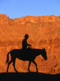 Cowboy on Mule Silhouetted Against Sandstone Cliff, Moab, Utah, USA Fotografie-Druck von Curtis Martin