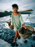 A Girl Gathers Salt Water in Lontar Leaf Buckets for Salt Making, Kusamba, Indonesia Photographie par Adams Gregory
