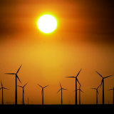 A Group of Wind Turbines are Silhouetted by the Setting Sun Photographic Print by Charlie Riedel