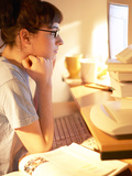 Young Woman Reading from Her Desktop Computer Screen and Studying Photographic Print
