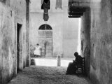 An Alley of Rome Where a Woman Sitting on a Chair is Working at a Piece of Crocheting Photographie