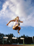 Low Angle View of a Female Athlete Jumping Over a Hurdle Photographic Print