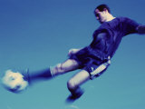 Soccer Player Jumping in Mid Air to Kick a Soccer Ball Photographic Print