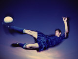 Young Man Kicking a Soccer Ball in Mid Air Lámina fotográfica Young Man Kicking a Soccer Ball in Mid Air Lámina fotográfica