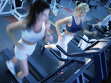 High Angle View of Two Young Women Running on Treadmills in a Gym Photographic Print