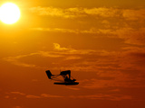 A Pilot Flies a Small Plane Past the Setting Sun Over Lake Winnipesaukee Photographic Print
