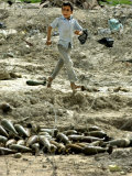 An Iraqi Schoolboy Walks Past a Pile of Unexploded Mortar Rounds in a Field in Basra, Iraq Photographie