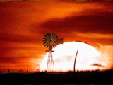 A Blazing Sun Drops Behind a Windmill Photographic Print