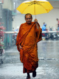 A Buddhist Monk Walks in the Rain on a Street in Bangkok Photographic Print