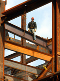 A Construction Worker Stands on a Steel Beam While Working on a High Rise Building Photographic Print