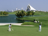 Men on Dubai Creek Golf with Yacht Club in Distance, Dubai, United Arab Emirates Photographic Print by Holger Leue