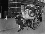 Young Boy Pulls Cartload of Possessions While Mother Pushes from Behind Premium fotografisk trykk av George J. Barry