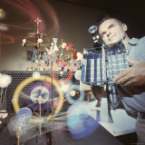 Architect/Designer Charles Eames with Engine that Generates Solar Power to Run Toys Surrounding Him Lámina fotográfica de primera calidad por Ralph Crane Architect/Designer Charles Eames with Engine that Generates Solar Power to Run Toys Surrounding Him Lámina fotográfica de primera calidad por Ralph Crane