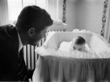 Sen. Jack Kennedy Admiring Baby Caroline as She Lies in Her Crib in Nursery at Georgetown Home Photographic Print by Ed Clark