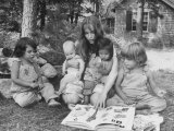 Actress Mia Farrow Reading to Her Adoptive Vietnamese Daughter Lark and Others Outside at Home Premium Photographic Print by Alfred Eisenstaedt