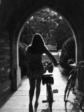 College Co-Ed Walking Bicycle Through an Archway on the Campus of Princeton University Photographie par Alfred Eisenstaedt