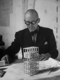 Architect Le Corbusier Studying Architectural Plans and Small Model of Building in His Office Reproduction photographique sur papier de qualité par Nina Leen