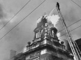 Fireman on Ladder Using a Hose to Extinguish Blazing Building Set Afire Photographic Print by Hans Wild