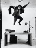 Architect and Designer Frank Gehry Jumping on a Desk in His Line of Cardboard Furniture Reproduction photographique sur papier de qualité par Ralph Morse
